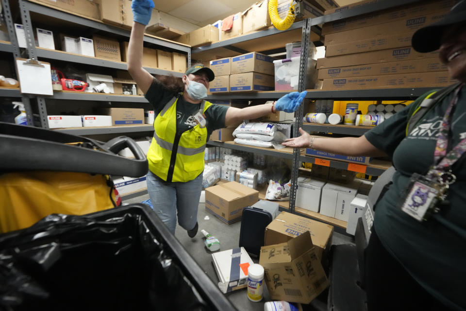 Los Angeles Food Bank custodian Maria Recinos is found safe by her team members as they practice a "drop, cover, and hold on" simulation at a ShakeOut earthquake drill at the Los Angeles Regional Food Bank in Los Angeles Thursday, Oct. 19, 2023. Up and down the West Coast, the ShakeOut drill was scheduled to begin at 10:19 a.m. PDT with a cellphone-rattling test alert from the region's ShakeAlert earthquake warning system. (AP Photo/Damian Dovarganes)