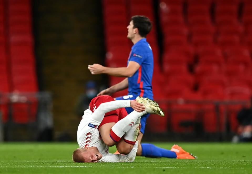 Kasper Dolberg rolls away in pain after the challenge that resulted in Harry Maguire’s second yellow card.