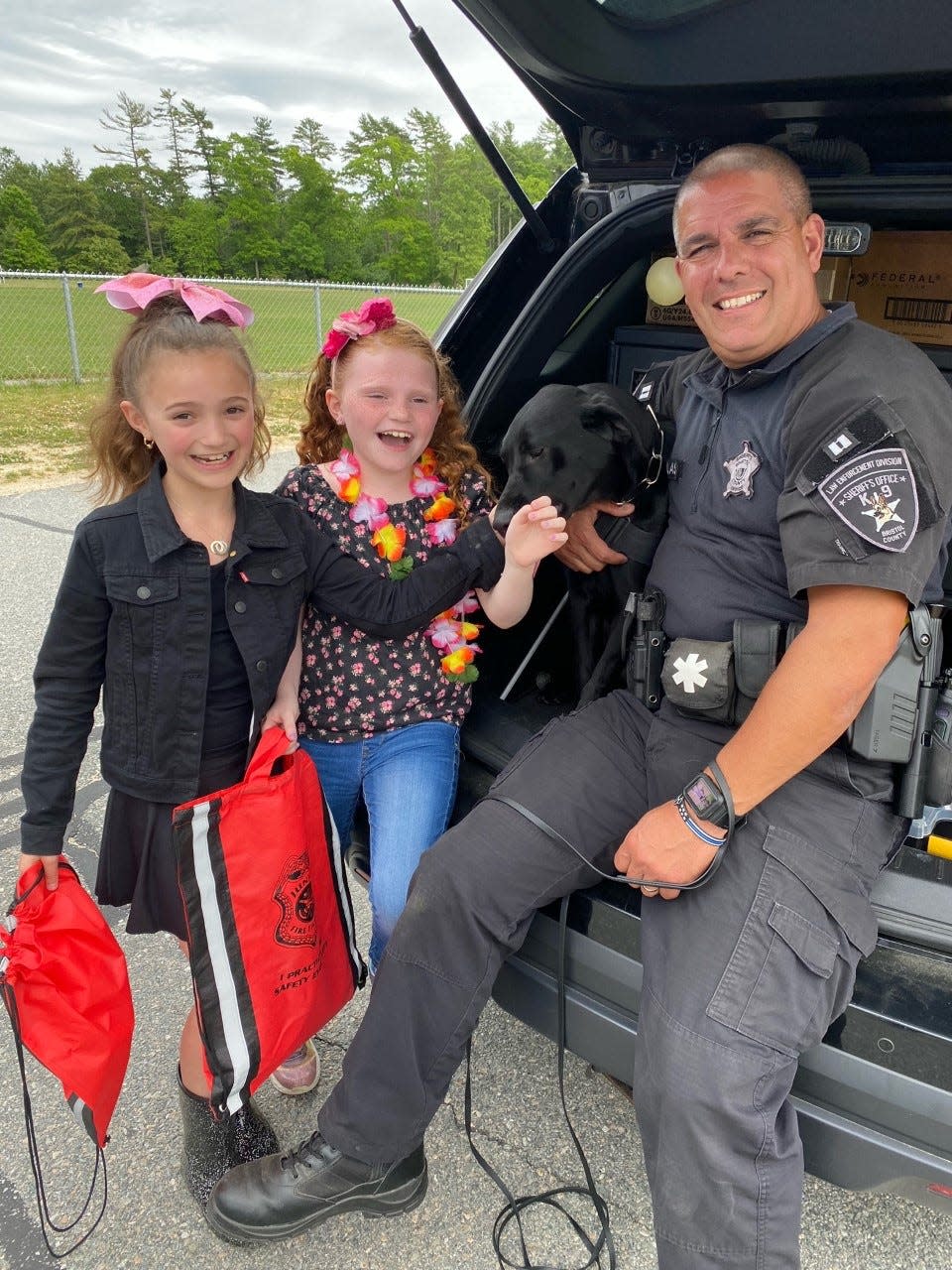 Capt. Paul Douglas of the Bristol County Sheriff's Department is seen with Huntah, the labrador retriever he handles, as children from Acushnet Elementary School enjoy their company at a public safety activity day on Wednesday, June 1.