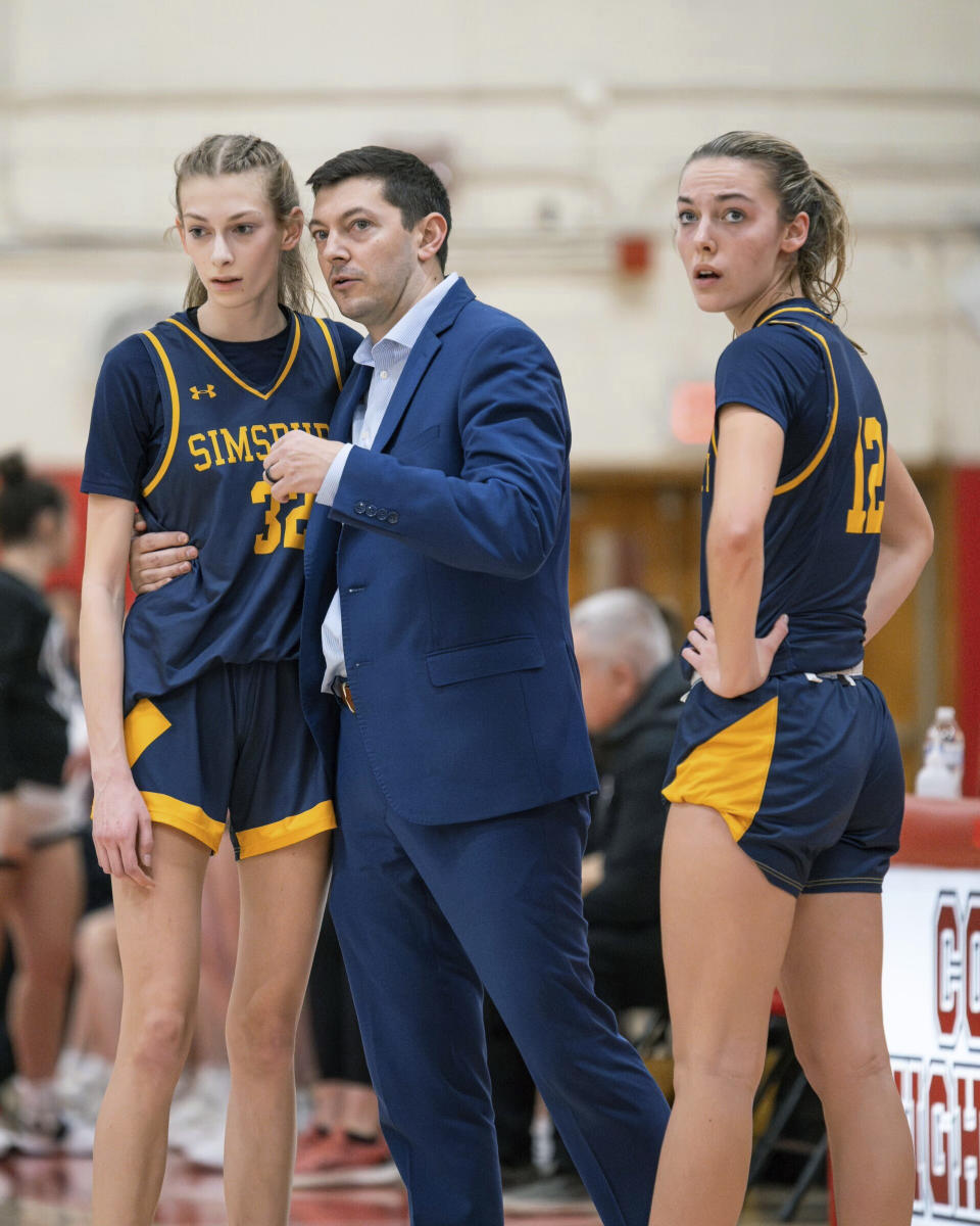 This photo provided by Scott Kerr shows Simsbury High School girls basketball coach Sam Zullo talking to players Amanda Gallagher, left, and Olivia Jarvis during a game earlier this season. Sam Zullo will coach for the Connecticut state high school title on Saturday, March 16, 2024, the same day his father Jim Zullo will coach the Northville High School girls in the New York state high school semifinals. (Scott Kerr via AP)