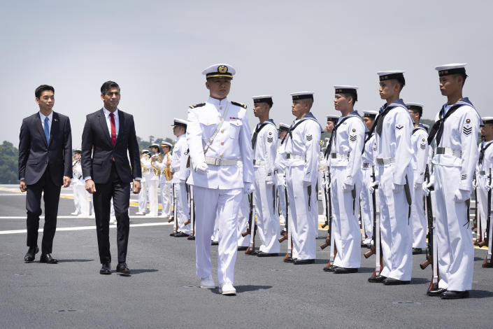 British Prime Minister Rishi Sunak, second left, and Japan's Vice Defense Minister Toshiro Ino, left, inspect a guard of honour on board the Japanese aircraft carrier, JS Izumo, during a visit to the Japan Maritime Self-Defence Force (JMSF) at Yokosuka Naval Base, south of Tokyo, ahead of the G-7 Summit in Hiroshima, Thursday, May 18, 2023. (Stefan Rousseau/Pool Photo via AP)