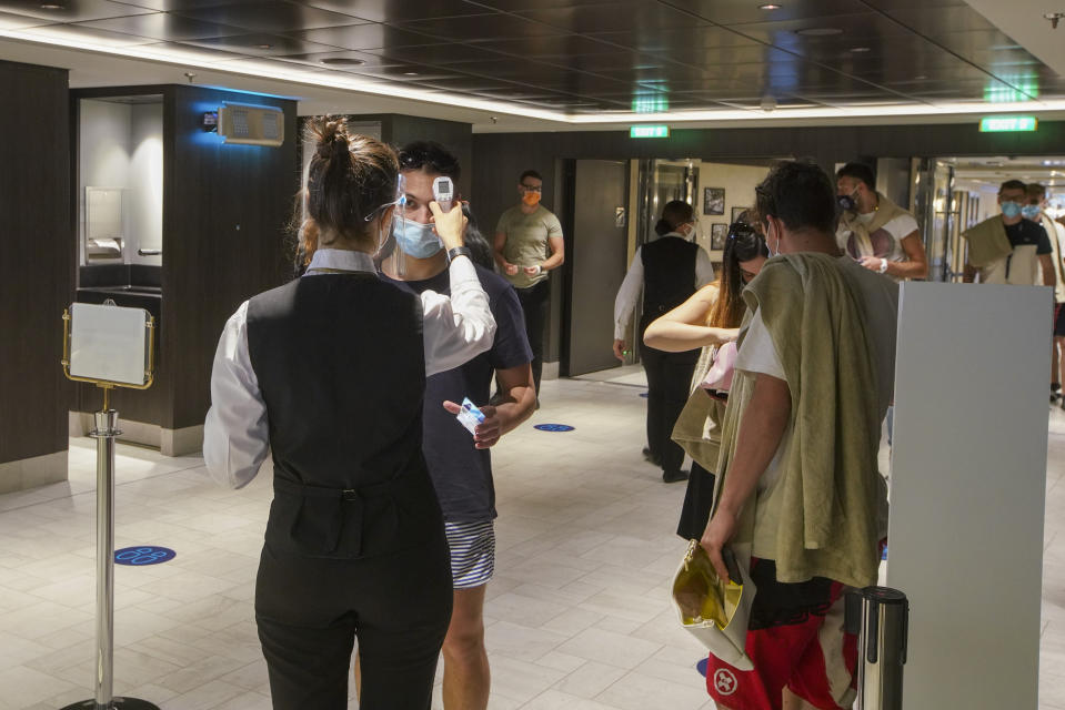 Passengers have their body temperature measured as they enter a restaurant of the MSC Grandiosa cruise ship in Civitavecchia, near Rome, Wednesday, March 31, 2021. MSC Grandiosa, the world's only cruise ship to be operating at the moment, left from Genoa on March 30 and stopped in Civitavecchia near Rome to pick up more passengers and then sail toward Naples, Cagliari, and Malta to be back in Genoa on April 6. For most of the winter, the MSC Grandiosa has been a lonely flag-bearer of the global cruise industry stalled by the pandemic, plying the Mediterranean Sea with seven-night cruises along Italy’s western coast, its major islands and a stop in Malta. (AP Photo/Andrew Medichini)