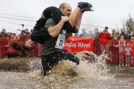 Richard Cannon carries Annie Leslie through the water pit while competing in the North American Wife Carrying Championship at Sunday River ski resort in Newry, Maine October 11, 2014. REUTERS/Brian Snyder