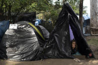 FILE - In this May 26, 2021 file photo, a woman rests in a tent on land designated for a Petrobras refinery, called the "First of May Refugee Camp," which refers to the date the squatters camp sprung up during the new coronavirus pandemic in Itaguai, Rio de Janeiro state, Brazil. In the first quarter of 2021, Brazil saw its highest unemployment and economic inequality in at least nine years, with the cost of living surging and tent cities and shantytowns emerging. (AP Photo/Silvia Izquierdo, File)