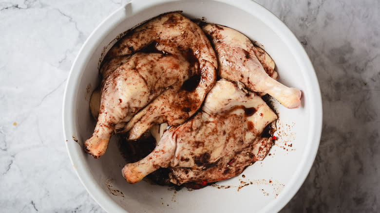 Duck legs in marinade in white bowl