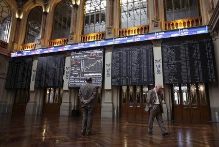 A trader looks at computer screens as another one talks on his mobile phone at the Madrid stock exchange September 11, 2014. REUTERS/Andrea Comas