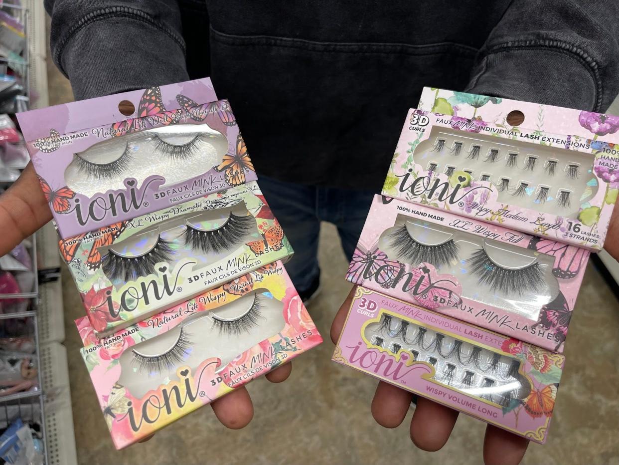 Hands holding out Ioni false lashes in packaging decorated with flowers and butterflies.