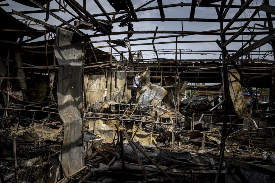 A man collects copper wires from the bombed-out shell of the market. 