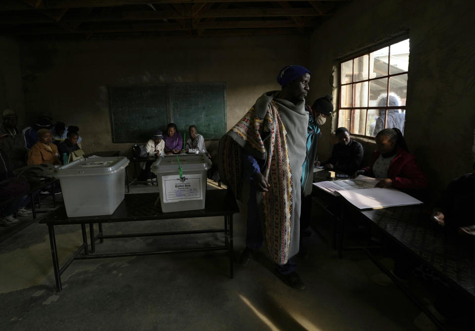 A man wearing a blanket waits as an official checks his name on the electoral register at a poling station in Maseru, Lesotho, Friday, Oct. 7, 2022. Voters across the picturesque mountain kingdom of Lesotho are heading to the polls Friday to elect a leader to find solutions to high unemployment and crime. (AP Photo/Themba Hadebe)