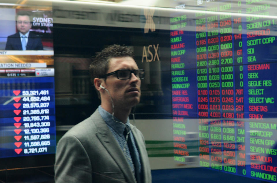 A investor looks at share price monitors through the window at the Australian Stock Exchange.