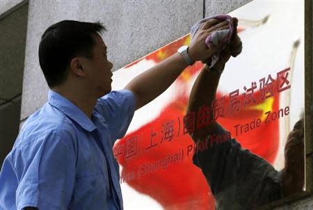 A reflection of the Chinese national flag is seen in a sign for the new China (Shanghai) Pilot Free Trade Zone, as a worker cleans it, in Shanghai, September 29, 2013. REUTERS/Stringer