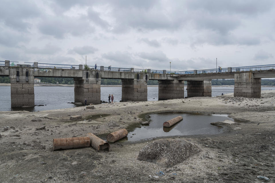 People walk on a central beach as a water in Dnipro river dropped for more than 4 meters after the explosion of the Kakhovka dam in Zaporizhzhia, Ukraine, Sunday, July 9, 2023. (AP Photo/Evgeniy Maloletka)