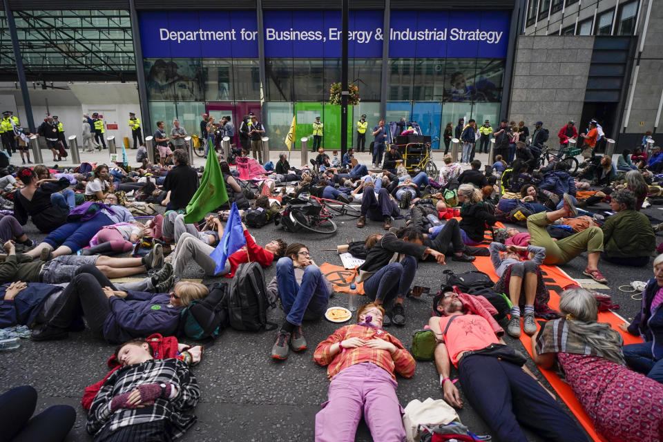 FILE - Demonstrators lay in front of the Department for Business, Energy and Industrial Strategy during a protest organized by the climate activists group Extinction Rebellion in London on Aug. 26, 2021. The U.K. division of climate change protest group Extinction Rebellion says its activists would temporarily stop blocking busy roads, gluing themselves to buildings and engaging in other acts of civil disobedience because such methods have not achieved their desired effects. (AP Photo/Alberto Pezzali, File)