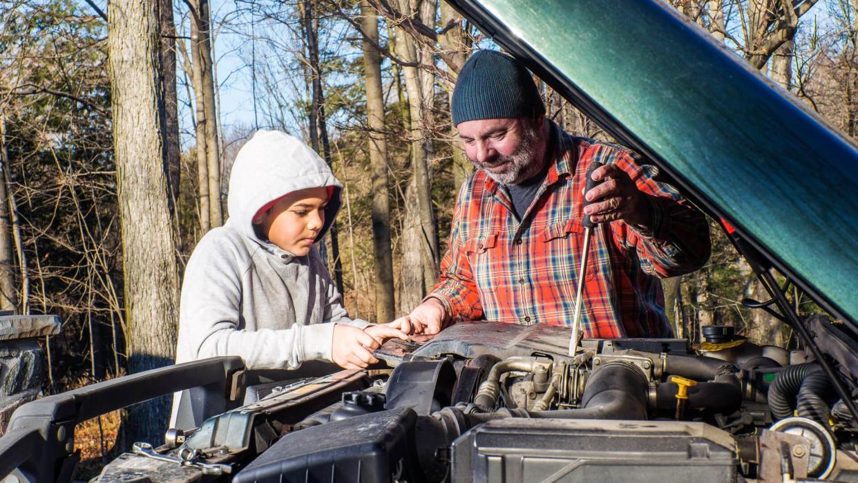 A father teaching his son about vehicle maintenance.