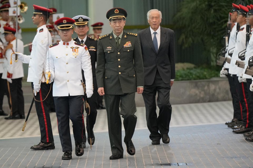 Chinese Defense Minister Gen. Li Shangfu, center, inspects the honor guard with Singapore Defense Minister Ng Eng Hen, right, during his official visit to the defense ministry in Singapore, Thursday, June 1, 2023. China and Singapore laid the groundwork Friday for a hotline between the two countries that would establish a high-level communications link between Beijing and a close American partner in Asia at a time when Chinese tensions with Washington are high and dialogue has stalled. (AP Photo/Vincent Thian)