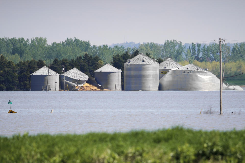In this May 10, 2019 photo, grain bins belonging to Brett Adams are surrounded by flood waters, in Peru, Neb. Adams had thousands of acres under water, about 80 percent of his land, this year. The water split open his grain bins and submerged his parents' house and other buildings when the levee protecting the farm broke. (AP Photo/Nati Harnik)