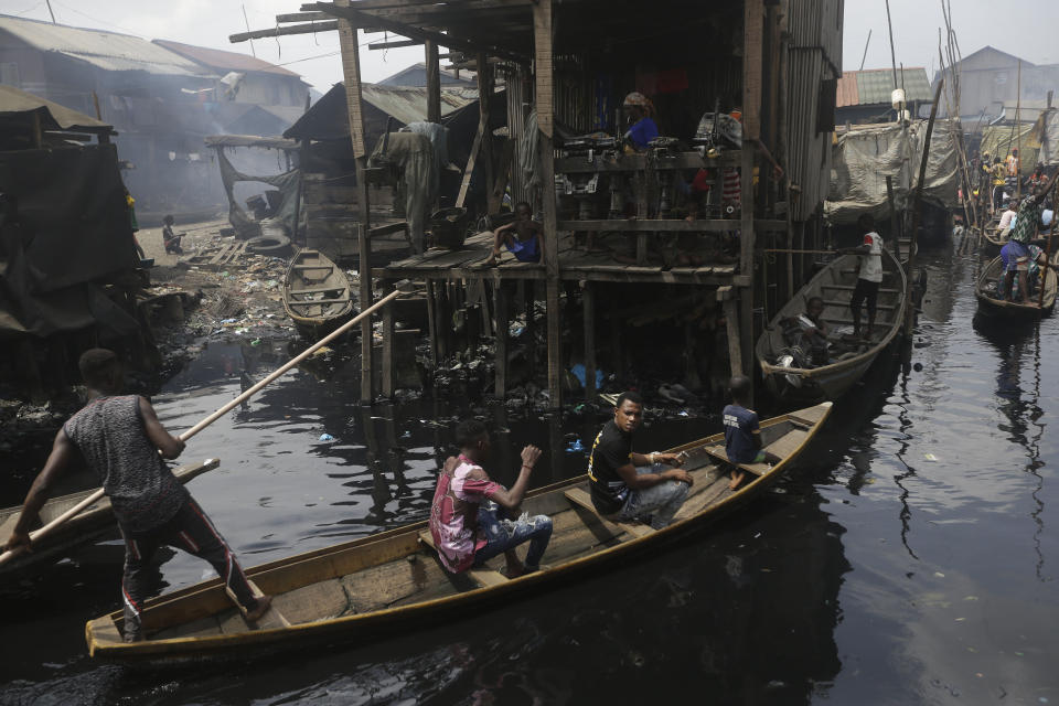 FILE - In this March 21, 2020, file photo, people travel by canoe in the floating slum of Makoko in Lagos, Nigeria. A global “brain drain” of medical professionals to richer countries has left developing nations in Africa, Southeast Asia, Latin America and elsewhere without tens of thousands of highly skilled workers to help combat the coronavirus. (AP Photo/Sunday Alamba, File)