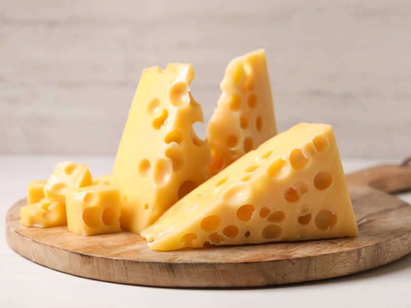 Pieces of delicious cheese on white wooden table