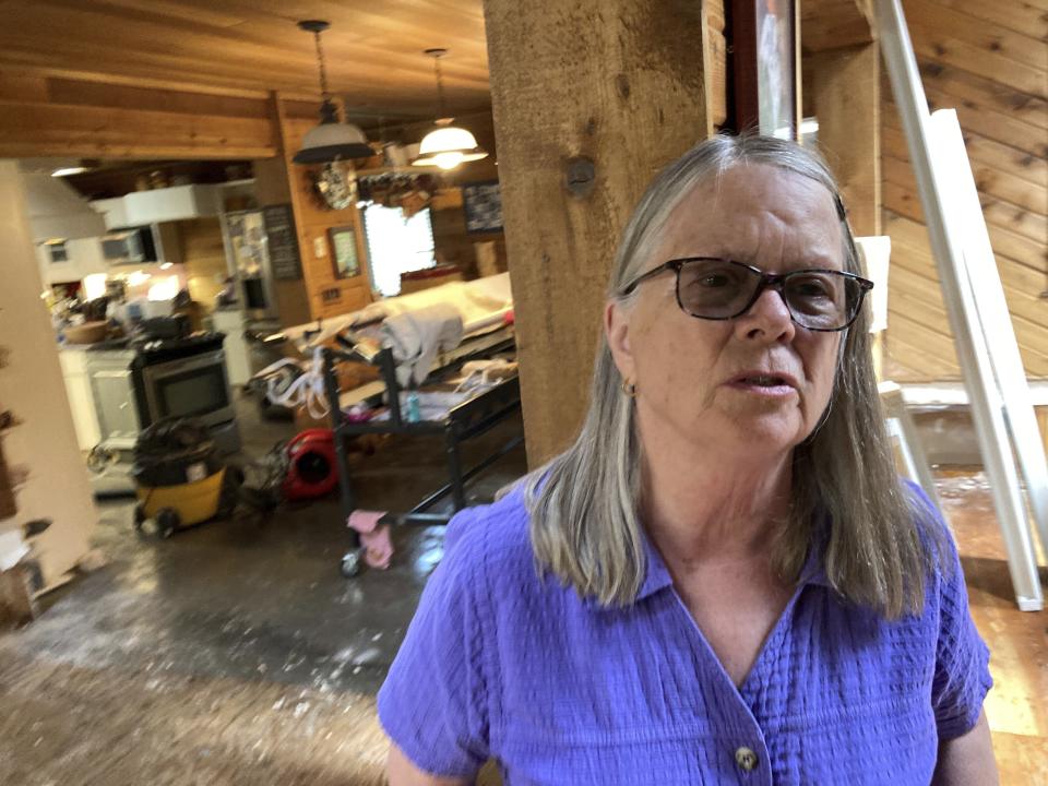 Chris Winter stands in her home in Juneau, Alaska, on Monday, Aug. 7, 2023, after a weekend glacial lake outburst flood resulted in about three inches of water in the raised home, which damaged flooring and insulation. City officials said water levels had returned to normal Monday but that banks along the river remained unstable. (AP Photo/Becky Bohrer)