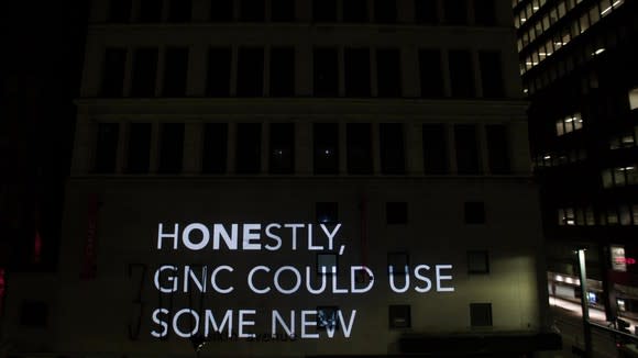 Projected GNC ad message on the side of a building.