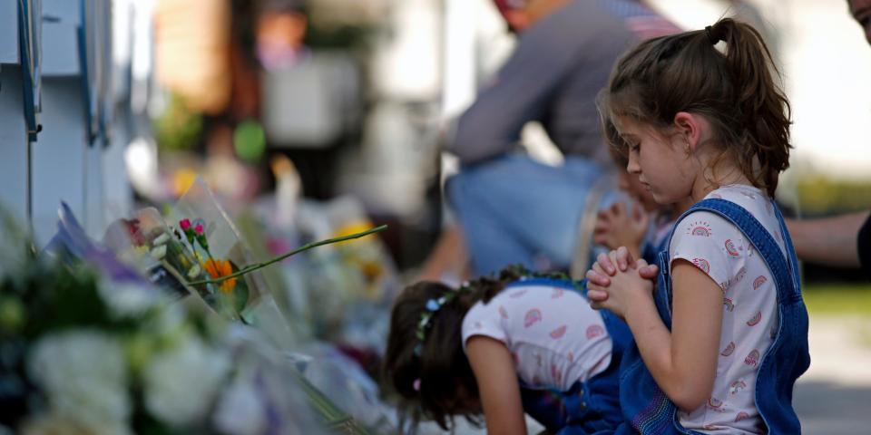 A young girl prays in front of a memorial site.
