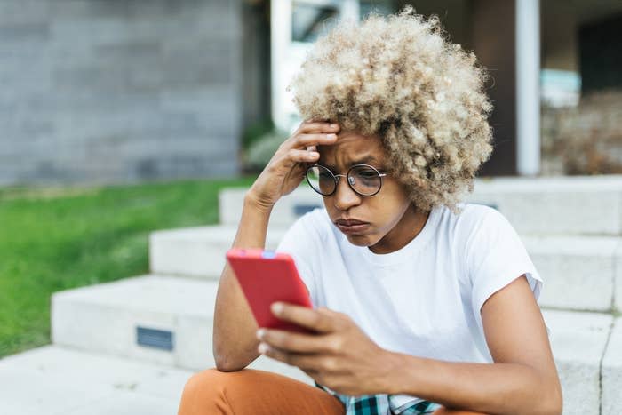 Young woman looking worried and stress while reading news on her mobile phone