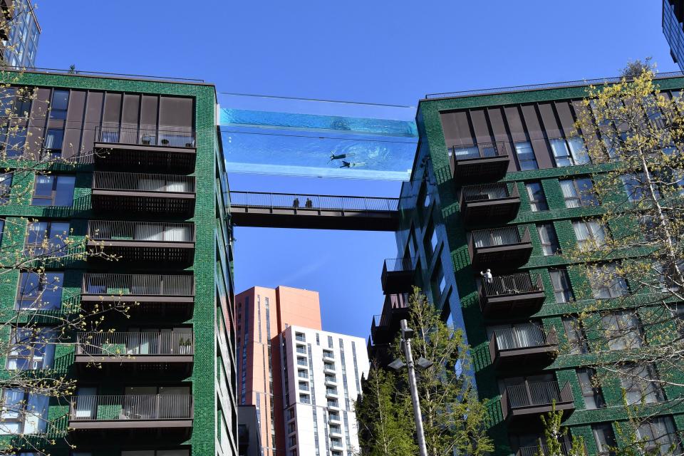 Models swim in a transparent acrylic swimming pool bridge that is fixed between two apartment blocks at Embassy Gardens next to the new US Embassy in south-west London on April 22, 2021. - A world first, the transparent 25-metre-long outdoor pool, known as the Sky Pool, will allow residents to swim from one building to the other, 10 storeys above the ground. (Photo by Justin TALLIS / AFP) (Photo by JUSTIN TALLIS/AFP via Getty Images)