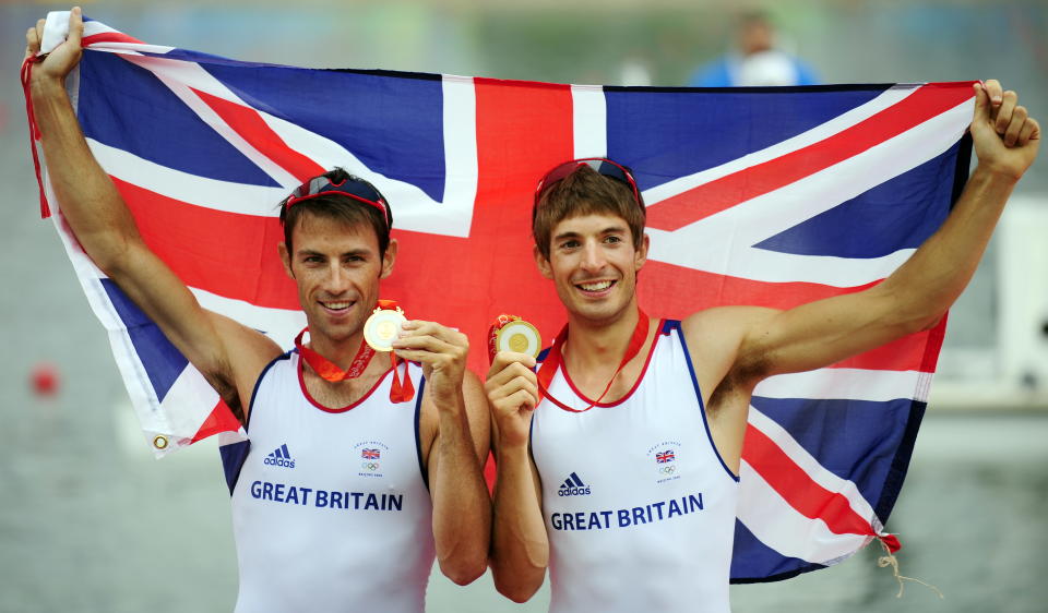 Britain's Zac Purchase and Mark Hunter celebrate on the podium during the medals ceremony for the lightweight men's double sculls at the Shunyi Rowing and Canoeing Park in Beijing  on August 17, 2008.  Britain won gold, Greece silver and Denmark bronze.   AFP PHOTO / FRED DUFOUR (Photo by Fred DUFOUR / AFP) (Photo by FRED DUFOUR/AFP via Getty Images)