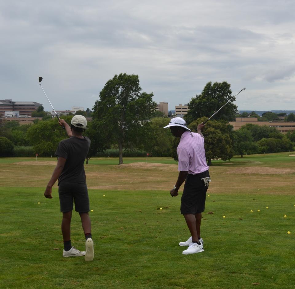 FabGolf instructor Orlando Peace works with Rogers High School junior Jamari, who is both a golfer and a summer counselor in this year's program.