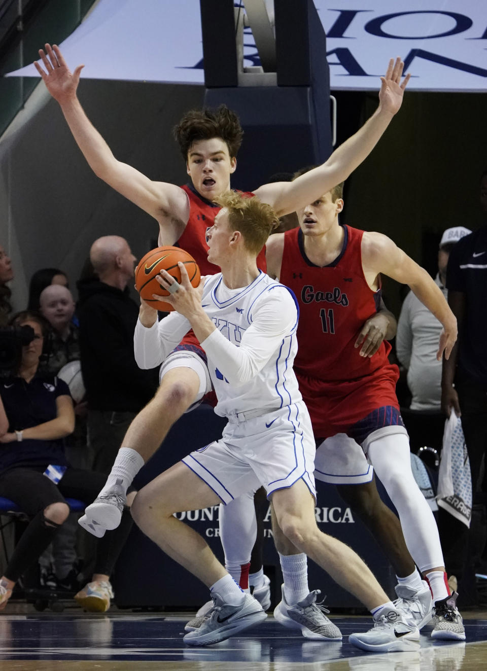Saint Mary's guard Alex Ducas defends against BYU guard Richie Saunders, front, as Saint Mary's center Mitchell Saxen (11) blocks out during the first half of an NCAA college basketball game Saturday, Jan. 28, 2023, in Provo, Utah. (AP Photo/George Frey)