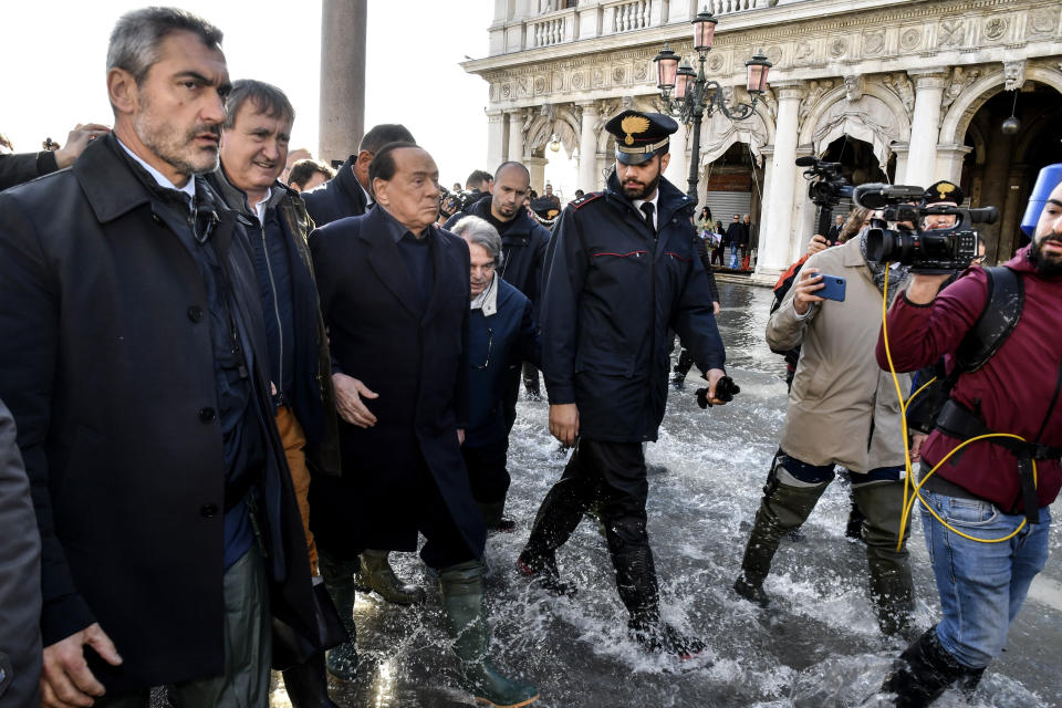 Former Italian Premier Silvio Berlusconi, 3rd from left, flanked by Venice mayor Luigi Brugnaro, left, and MP Renato Brunetta, wades through water in St. Mark's Square in Venice, Italy, Thursday, Nov. 14, 2019. The worst flooding in Venice in more than 50 years prompted calls to better protect the historic city from rising sea levels as officials calculated hundreds of millions of euros in damage. (AP Photo/Luigi Costantini)