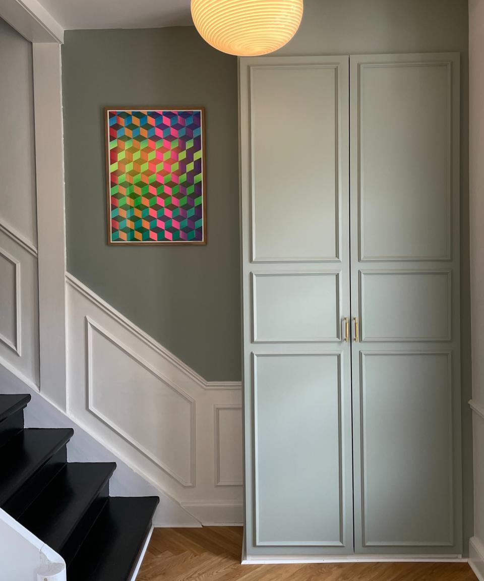 A hallway cabinet with moldings, painted sage green