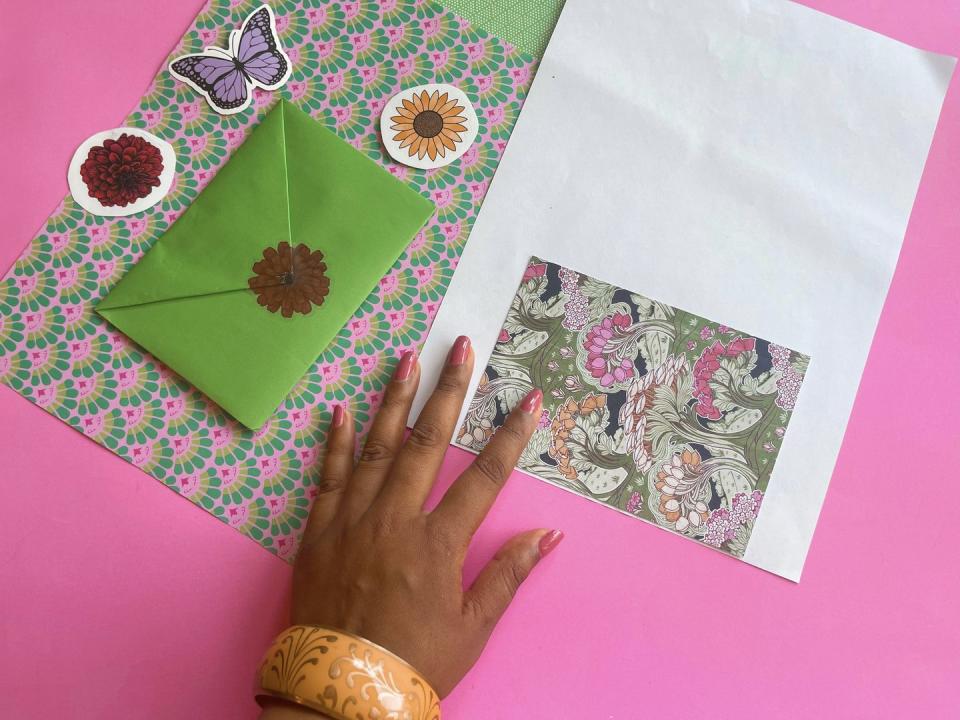 hand placing a postcard on a sheet of paper