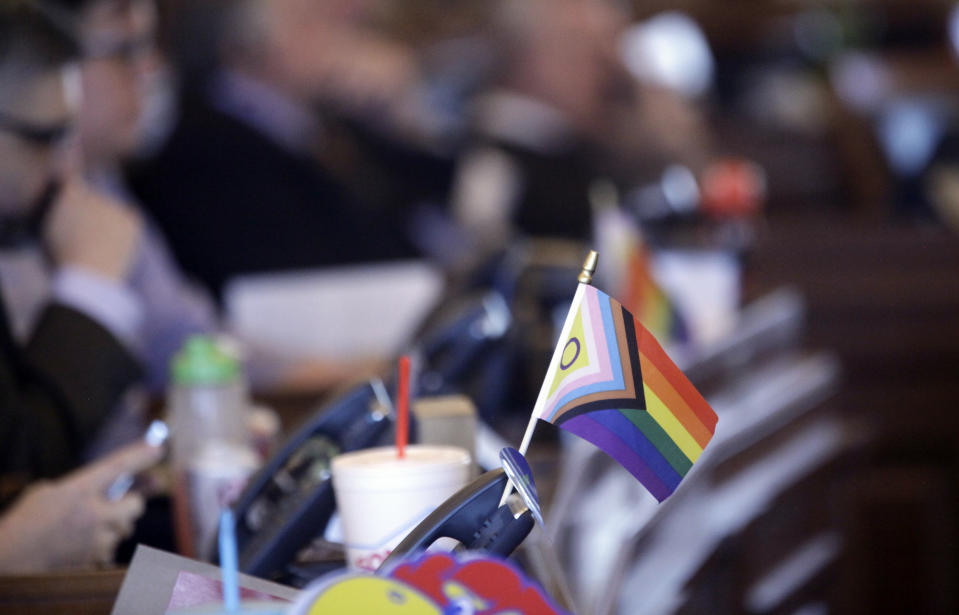 FILE - A small flag celebrating LGBTQ rights decorates a desk on the Democratic side of the Kansas House of Representatives during a debate, Tuesday, March 28, 2023, at the Statehouse in Topeka, Kan. U.S. states with laws restricting what bathrooms transgender kids can use in public schools are wrestling with how those laws will be enforced. At least 10 states have enacted such laws and transgender, nonbinary and gender-noncomforming people expect states to rely on what they call vigilante enforcement by private individuals. (AP Photo/John Hanna, File)