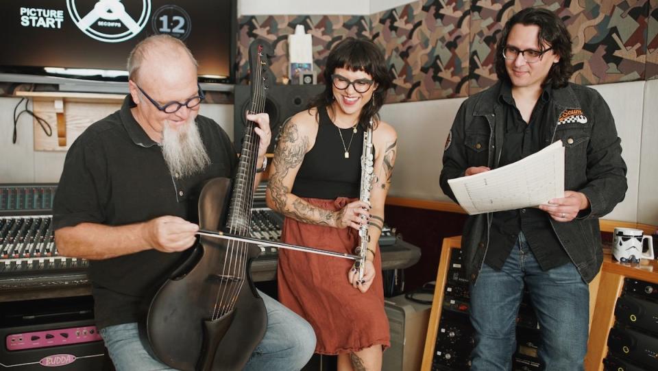 Kevin Kiner strums an instrument as his children Deana and Sean look on in a recording studio