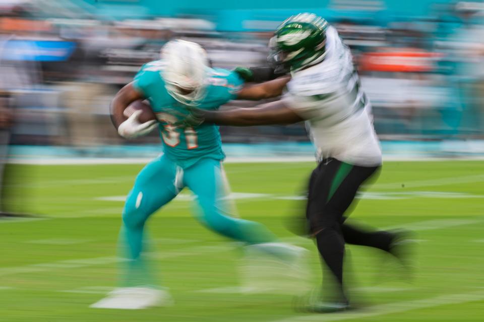 Miami Dolphins running back Raheem Mostert (31) stiff-arms New York Jets defensive end John Franklin-Myers (91) while on the run in the third quarter during the football game between the New York Jets and host Miami Dolphins at Hard Rock Stadium on Sunday, January 8, 2023, in Miami Gardens, FL.