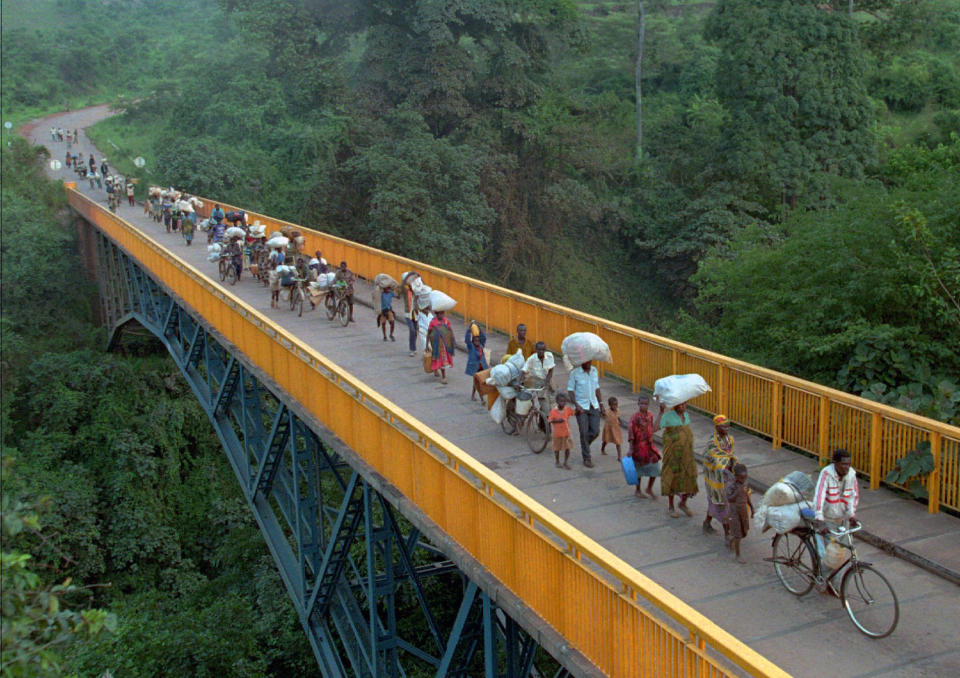 FILE - Rwandan refugees cross the bridge of Rumumo river which marks the border between Tanzania and Rwanda, Dec. 14, 1996. Hundreds of thousands of Rwandan refugees who fled their country after the 1994 civil war started their way towards Rwanda. (AP Photo/Ricardo Mazalan, File)
