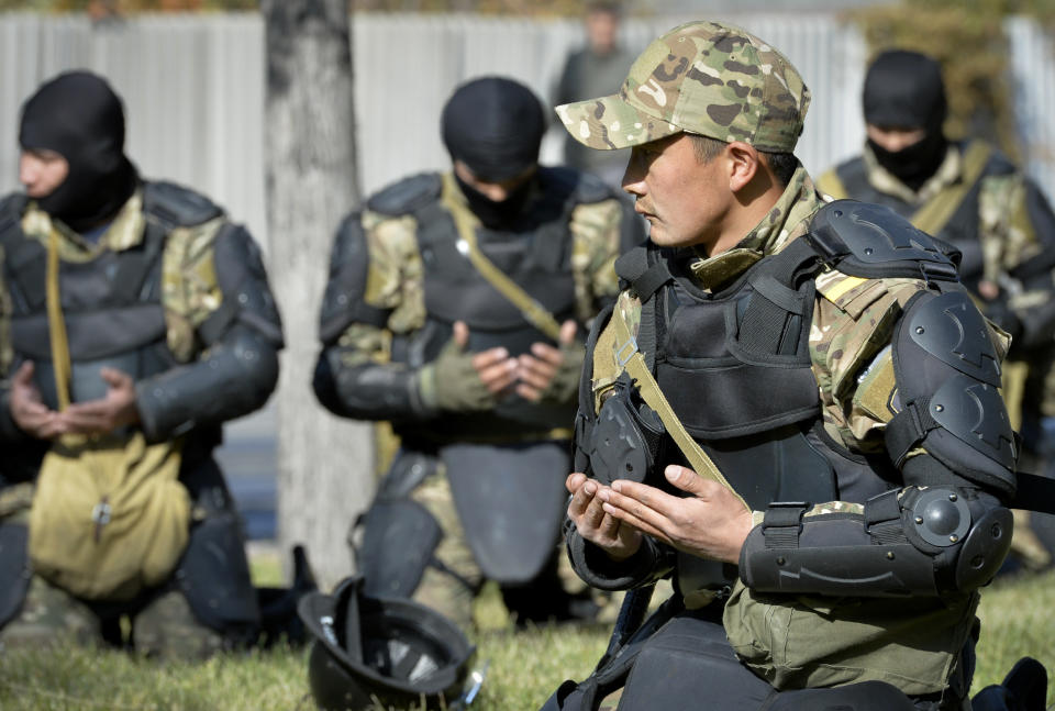 Kyrgyz police soldiers pray in a street in Bishkek, Kyrgyzstan, Thursday, Oct. 15, 2020. Kyrgyzstan President Sooronbai Jeenbekov announced his resignation on Thursday in a bid to end the turmoil that has engulfed the Central Asian nation after a disputed parliamentary election. (AP Photo/Vladimir Voronin)