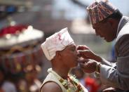 Jujubhai Bans Shrestha (L) gets his tongue pierced with an iron spike during the Tongue Penetration Festival at Bode near Kathmandu April 14, 2012. It is believed that after a volunteer from a Shrestha family successfully gets his tongue pierced in a spiritual trance with an iron spike and walks around the town shouldering a round bamboo rack with flaming torch, it brings good fortune to the villagers. REUTERS/Navesh Chitrakar