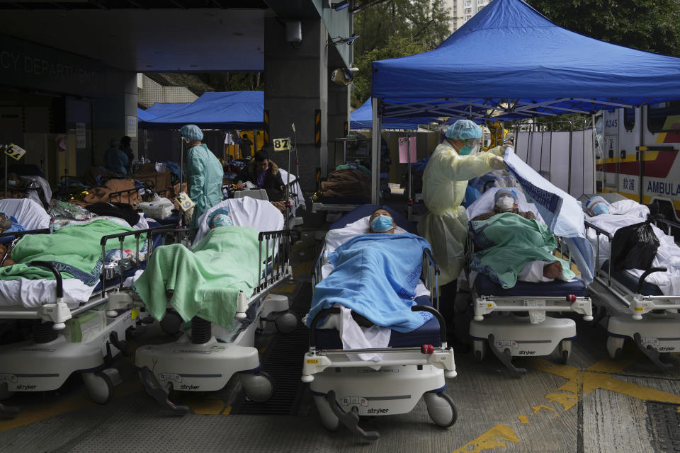 FILE - Patients lie on hospital beds as they wait at a temporary makeshift treatment area outside Caritas Medical Centre in Hong Kong, Friday, Feb. 18, 2022, as Hong Kong's hospitals reached 90% capacity on Thursday and quarantine facilities were at their limit, authorities said. (AP Photo/Kin Cheung, File)