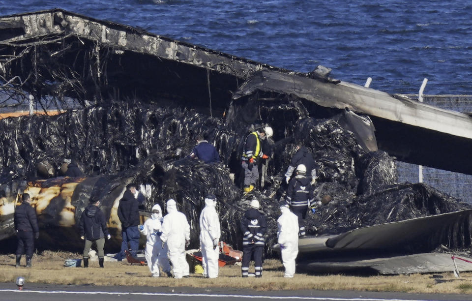 Officials investigate the wreckage of Japan Airlines plane at Haneda airport on Thursday, Jan. 4, 2024, in Tokyo, Japan. A transcript of communication between traffic control and two aircraft that collided and burst into flames at Tokyo’s Haneda Airport showed that only the larger Japan Airlines passenger flight was given permission to use the runway where a coast guard plane was preparing for takeoff. (Kyodo News via AP)