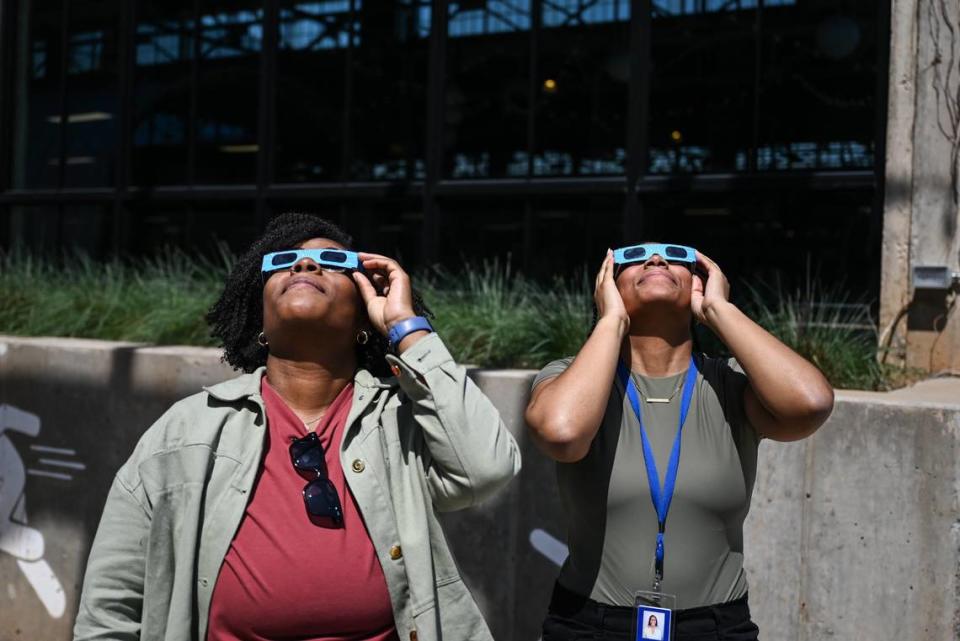 Sisters Lindsay Hughes, left, and Stephanie Hughes, view the solar eclipse through special glasses at Camp North End.