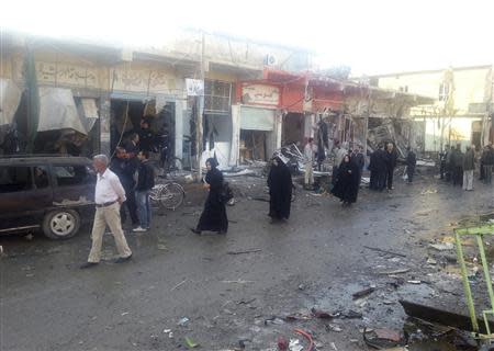 People walk past the site of bomb attacks in the town of Tuz Khurmato, 170 km (100 miles) north of the capital Baghdad, November 24, 2013. REUTERS/Stringer