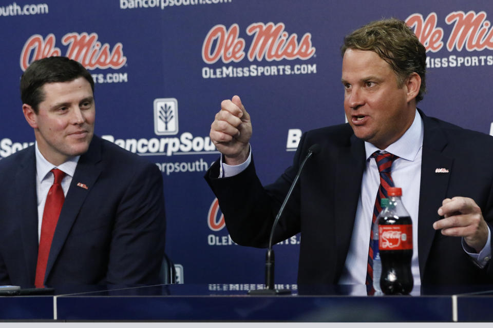Mississippi athletic director Keith Carter, left, reacts to Lane Kiffin as he answers a reporter's question at a news conference, moments after being introduced to Mississippi fans as their new college football coach, at The Pavilion, a multipurpose arena on the campus in Oxford, Miss., Monday, Dec. 9, 2019. Kiffin was previously, the football coach for three years at Florida Atlantic. (AP Photo/Rogelio V. Solis)
