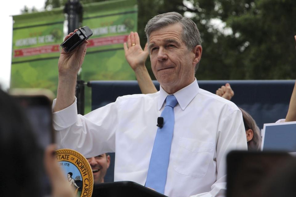 FILE - North Carolina Democratic Gov. Roy Cooper affixes his veto stamp to a bill banning nearly all abortions after 12 weeks of pregnancy at a public rally, May 13, 2023, in Raleigh, N.C. Transgender rights take center stage in North Carolina again Wednesday, Aug. 16, as GOP supermajorities in the General Assembly attempt to override the governor's vetoes of legislation banning gender-affirming health care for minors and limiting transgender participation in school sports. (AP Photo/Hannah Schoenbaum, File)