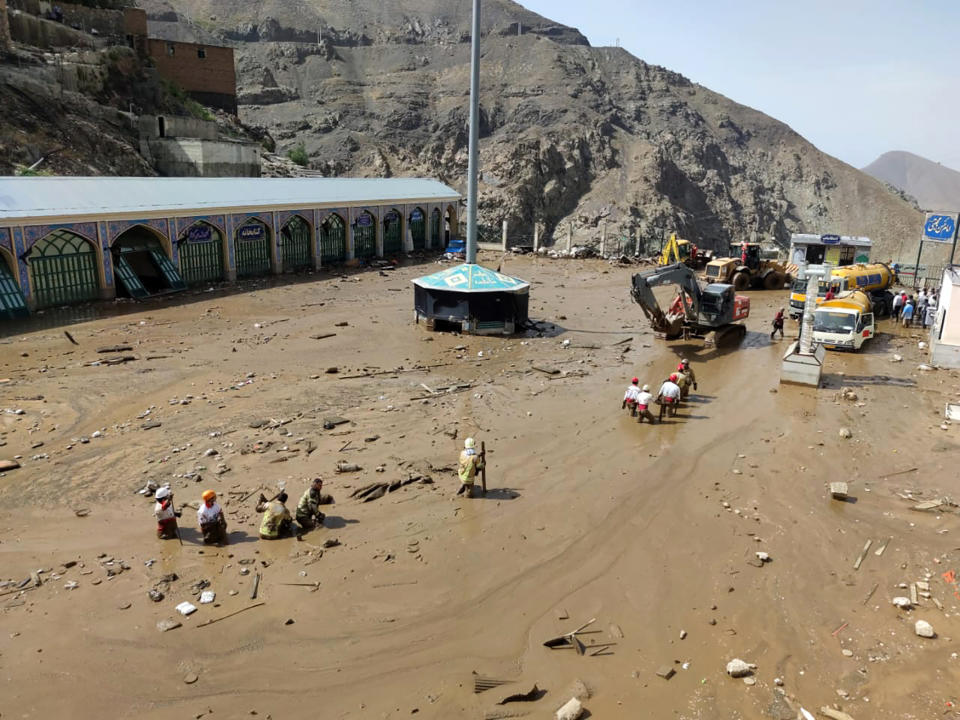 In this photo provided by the Iranian Red Crescent Society, members of a rescue team work at the site of a flash flood in the northwestern part of Tehran, Iran, Thursday, July 28, 2022. Heavy rains in the early hours of Thursday caused flash floods and then landslides and caused damage to Imamzadeh Davood, a religious shrine in the city. (Iranian Red Crescent Society via AP)