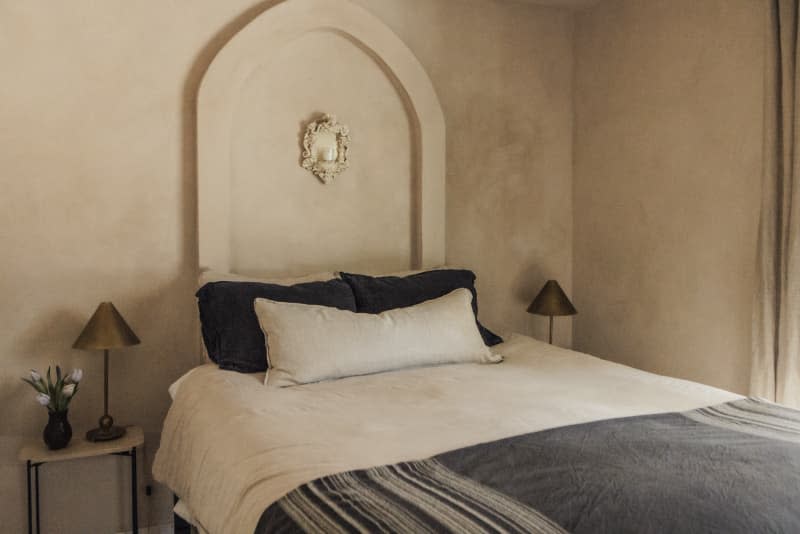 Bedroom with warm neutral textured walls and relief arch over bed