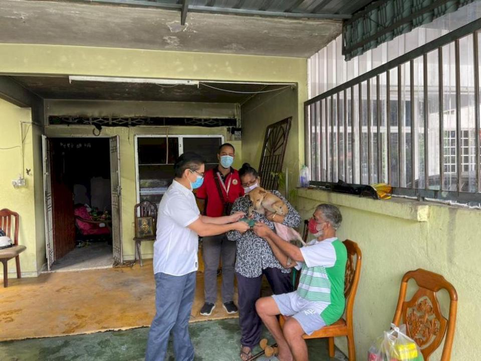 Pasir Bedamar assemblyman Terence Naidu presenting financial aid and provisions to N. Marimuthu whose house at Eastern Garden had been destroyed in an early morning fire on Wednesday. The family was saved from the fire by Anandaveli the dog. — Courtesy photo from Terence Naidu