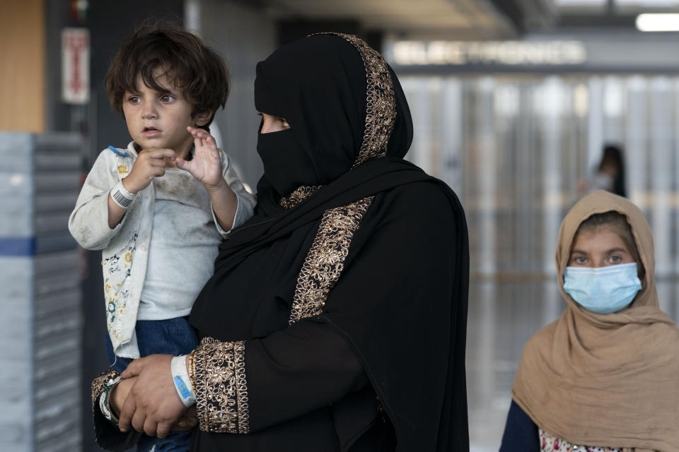 Families evacuated from Kabul, Afghanistan, walk through the terminal before boarding a bus after they arrived at Washington Dulles International Airport, in Chantilly, Va., on Friday, Aug. 27, 2021. (AP Photo/Jose Luis Magana)