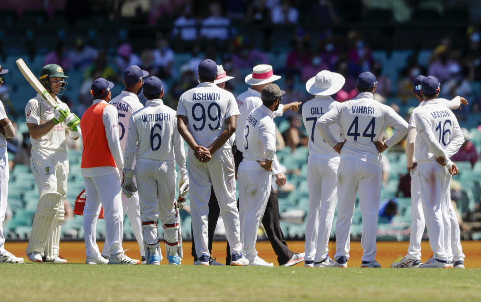 Australia's Tim Paine, left, waits as Indian players talk with the umpires over an issue with the crowd during play on day four of the third cricket test between India and Australia at the Sydney Cricket Ground, Sydney, Australia, Sunday, Jan. 10, 2021. (AP Photo/Rick Rycroft)